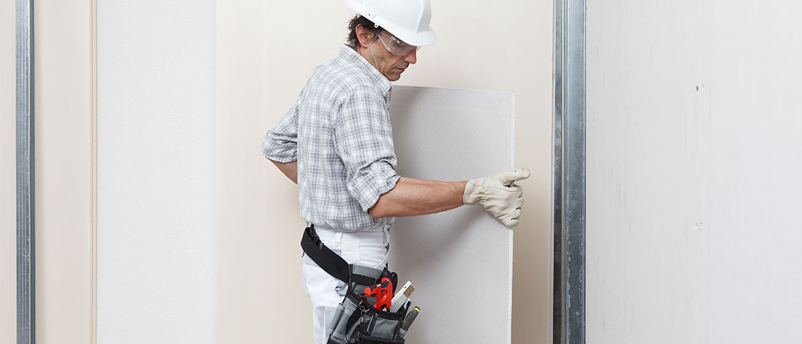 Tradesperson fitting drywall to an interior wall